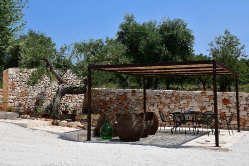 a pavilion with a table and chairs in front of a stone wall at Trulli di Titti - Luxury Country House in Castellana Grotte