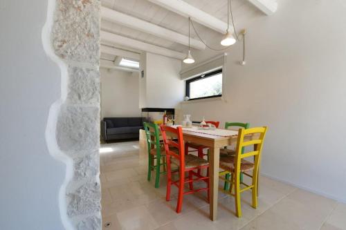 a dining room with a table and colorful chairs at Trulli di Titti - Luxury Country House in Castellana Grotte