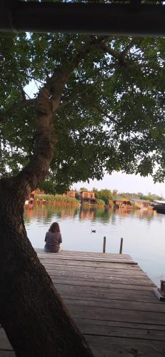 une personne assise sur un quai à côté d'une masse d'eau dans l'établissement Kucica Claus, à Ulcinj
