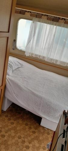 a bed in a small room with a window at Caravane hôte in Carhaix-Plouguer