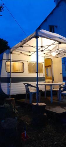 a white van with a table and chairs under a tent at Caravane hôte in Carhaix-Plouguer