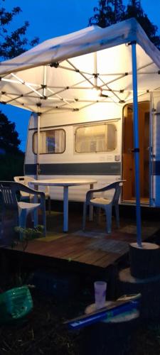 a rv with a table and chairs under a tent at Caravane hôte in Carhaix-Plouguer
