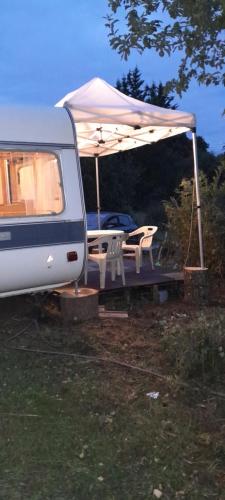 a camper with a table and chairs under a tent at Caravane hôte in Carhaix-Plouguer