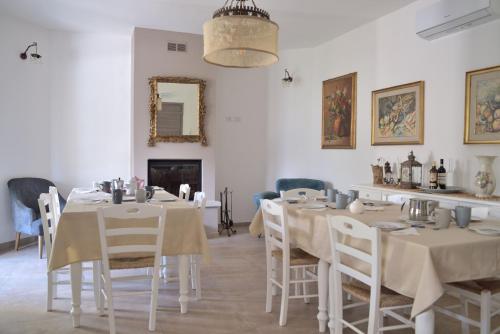 ein Esszimmer mit weißen Tischen, Stühlen und einem Spiegel in der Unterkunft La Rosa di Tempalta in Albanella