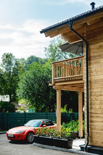 a red car parked next to a wooden house at Chalet 49 Nesselgraben - Ferienwohnungen aus Holz in Koppl