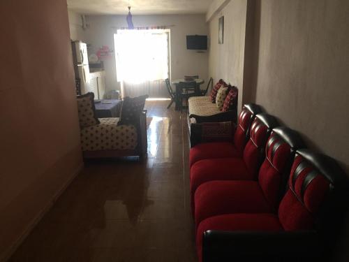 uma sala de estar com um sofá vermelho e cadeiras em Villa Said em Moulay Bousselham