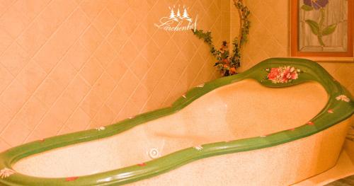 a bath tub in a pink bathroom with a green border at Hotel Garni Lärchenhof in Lech am Arlberg