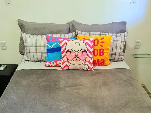 a bed with colorful pillows on top of it at Di Pipa Rooms - Hidromassagem Externa in Pipa