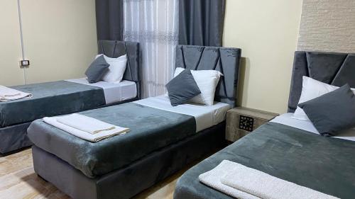 Habitación con 2 camas con cojines azules. en Petra Rose Apartment en Wadi Musa