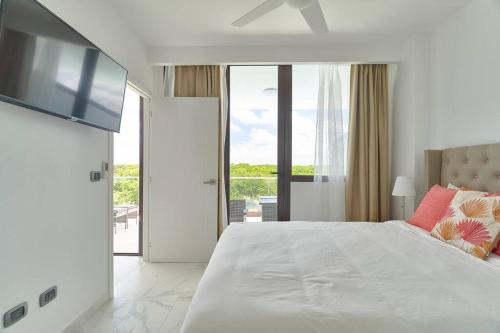 プンタ・カナにあるLuxury Apartment at Cana Rock Star Punta Cana DRの白いベッドルーム(大型ベッド1台、テレビ付)