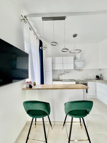 - deux chaises vertes dans une cuisine avec des armoires blanches dans l'établissement Le Malezi village des Pennes Mirabeau, aux Pennes-Mirabeau