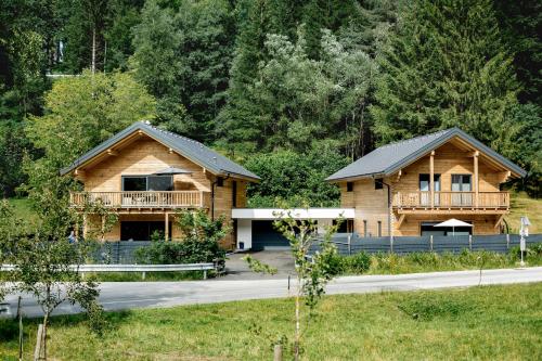two log homes on a road with trees at Chalet 49 Nesselgraben - Ferienwohnungen aus Holz in Koppl