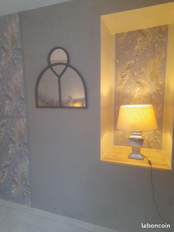 een lamp naast een spiegel bij La Caillourie in Bricquebec