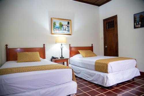 una habitación de hotel con 2 camas y una lámpara en Hotel Villa Serena Escalon, en San Salvador
