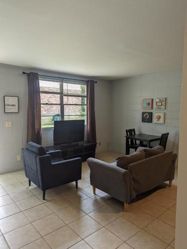 a living room with two couches and a flat screen tv at Pet friendly single story garden condominium in Gulfport