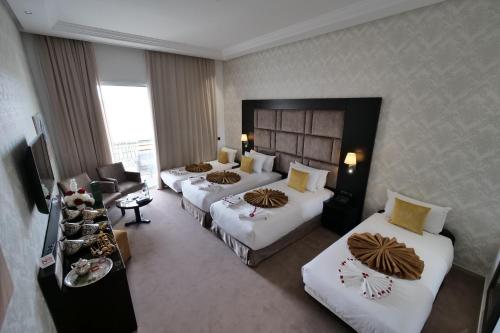 a hotel room with three beds and a couch at El Olivar Palace Marrakech All Inclusive, Aquapark & SPA in Marrakech