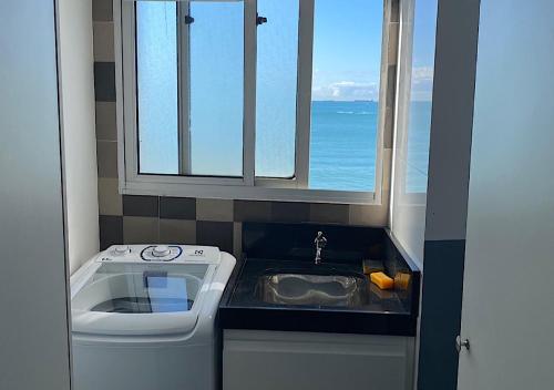 uma pequena cozinha com um lavatório e uma janela em Apartamento Renovado na beira da Praia em Vila Velha
