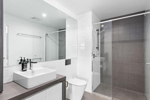 a white bathroom with a sink and a shower at Burleigh Beach Escape with Stunning Sunset Views in Gold Coast