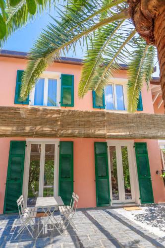 a pink house with green doors and two chairs at La Casa dei Glicini in Levanto