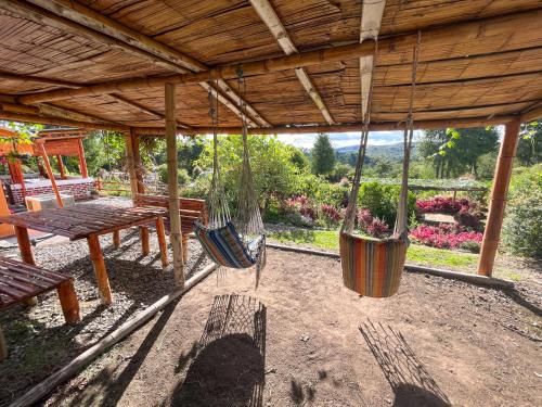 a porch with swings and a table and a bench at Campground Hostal La Bonanza Chez Kika in Piendamó