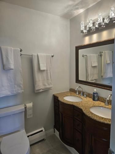 a bathroom with two sinks and a mirror and a toilet at Sunflower Guest Suites in Summerside