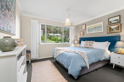 a bedroom with a blue bed and a window at 24 Hyam Rd Hyams Beach in Hyams Beach