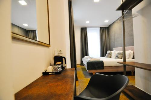 une chambre d'hôtel avec un lit et une chaise dans l'établissement Heritage Hotel Petrakija, à Sarajevo