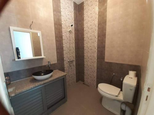 La salle de bains est pourvue de toilettes, d'un lavabo et d'un miroir. dans l'établissement Résidence de la plage Ghar El Melh, à Ghār al Milḩ