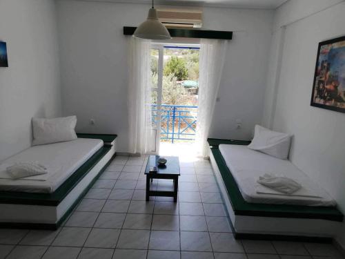 two beds in a room with a window and a table at Angistri's panorama apartments in Skala