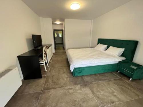 a bedroom with a green bed and a desk at Pensiunea PHILIA in Dubova