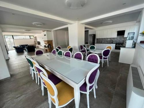 a dining room with a white table and purple chairs at Pensiunea PHILIA in Dubova