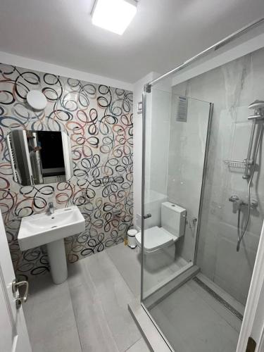 a bathroom with a shower and a toilet and a sink at Pensiunea PHILIA in Dubova
