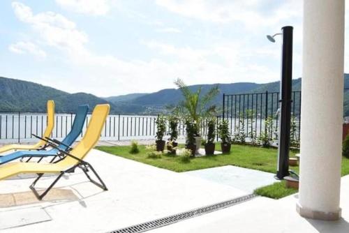 a yellow chair on a patio with a view of the water at Pensiunea PHILIA in Dubova