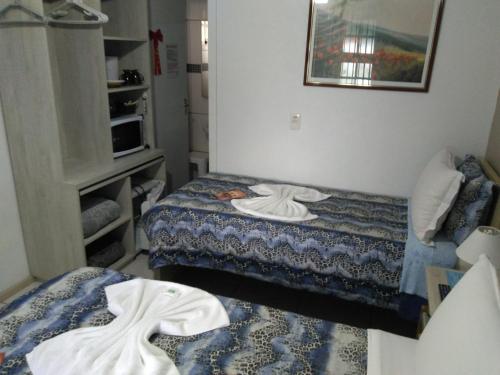 a small room with two beds and a microwave at Hospedagem Da Laranjeira Gramado in Gramado