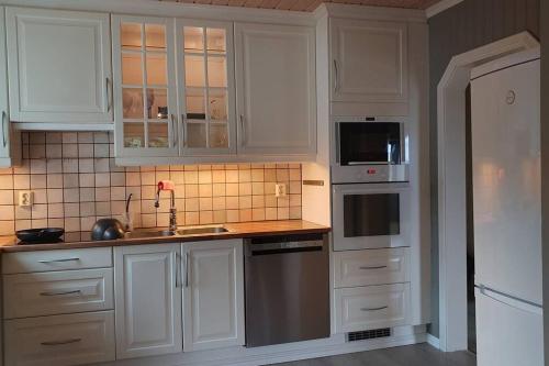 uma cozinha com armários brancos e electrodomésticos de aço inoxidável em Moen Booking em Åndalsnes