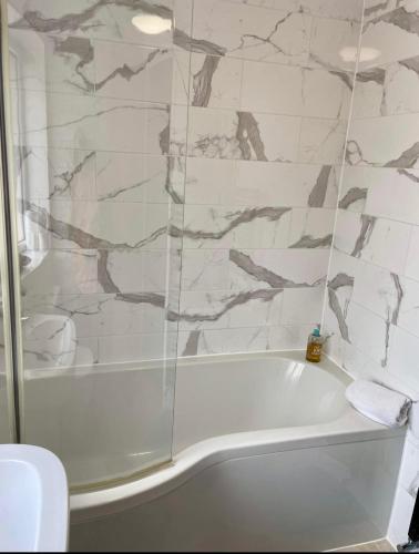 a white bath tub in a bathroom with marble walls at Adina s House 5 Bedrooms in Rugeley