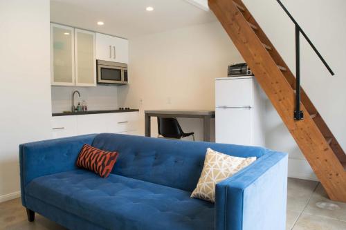 um sofá azul numa sala de estar com uma cozinha em English Cottage Guest House walk to the Grove and lots of attractions em Los Angeles