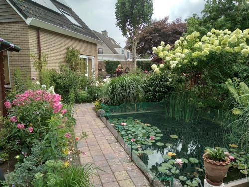 a garden with a pond with lilies and flowers at Kop vd Hondsrug1 in Haren