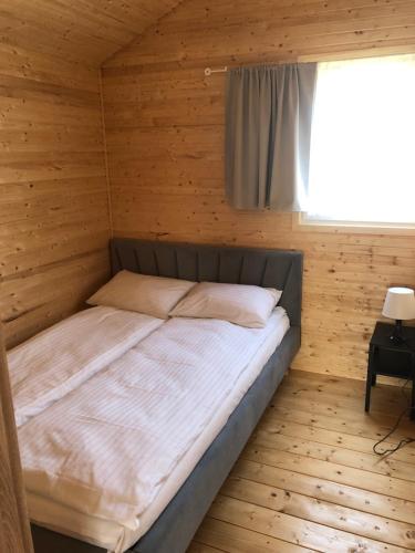 a bed in a wooden room with a window at Baltic Holidays in Gąski