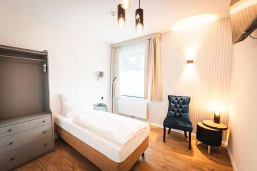 een slaapkamer met een bed, een stoel en een raam bij Hotel Elbe-Herz-Appartement in Wittenberge