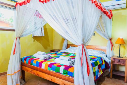 1 dormitorio con 1 cama con dosel en Aparthotel Jardin Tropical, en Buyumbura