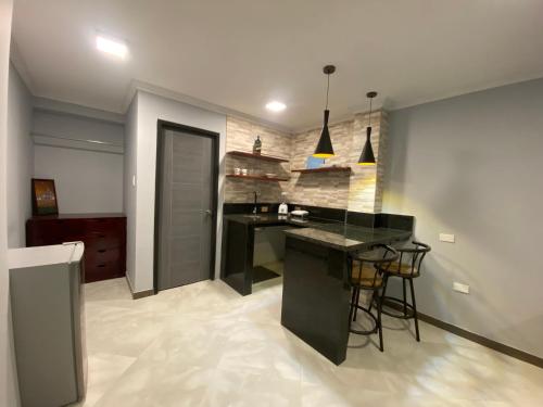 a kitchen with a black counter and chairs in a room at Suites AlojaT MIMOS Machala diagonal al oro verde. in Machala