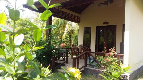 a porch of a house with chairs and plants at Adinda bungalaow in Gili Islands