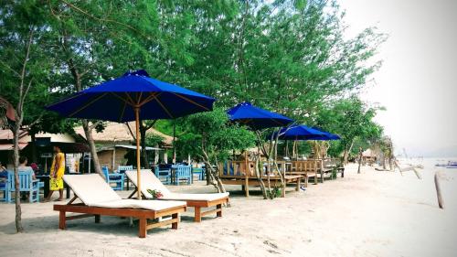a group of chairs and umbrellas on a beach at Adinda bungalaow in Gili Islands