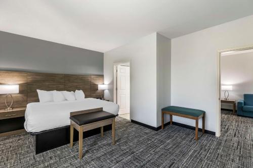 a hotel room with a large bed and a stool at Best Western Plus MidAmerica Hotel in Mascoutah