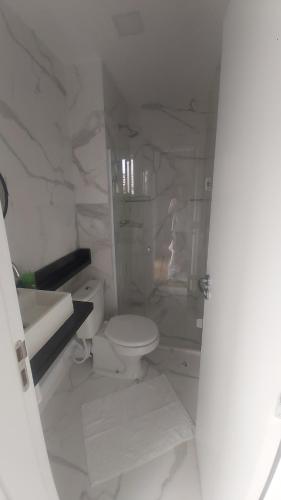 a white bathroom with a toilet and a sink at AP no Centro, Ao lado de Praça de Poços de Caldas in Poços de Caldas