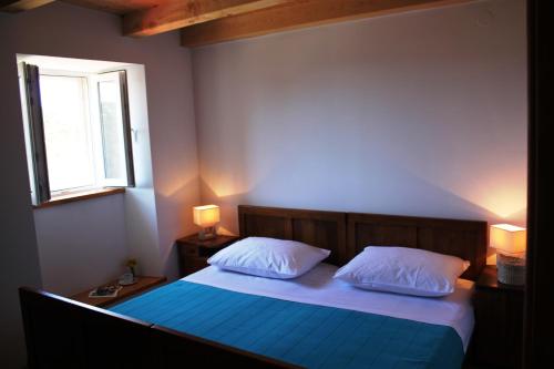 een slaapkamer met een bed met blauwe lakens en een raam bij Holiday Home Brotnice in Cavtat