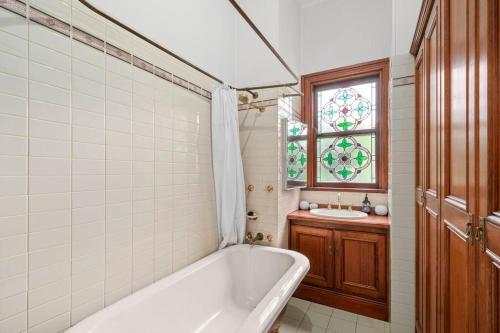 bagno con vasca, lavandino e finestra di Belle Vue Cottage - East Toowoomba a Toowoomba