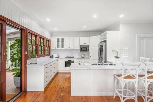 a white kitchen with white cabinets and white counter tops at Belle Vue Cottage - East Toowoomba in Toowoomba