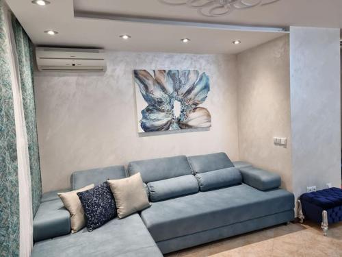 a living room with a blue couch and a painting at Oazis resort lux vip apartament in Lozenets